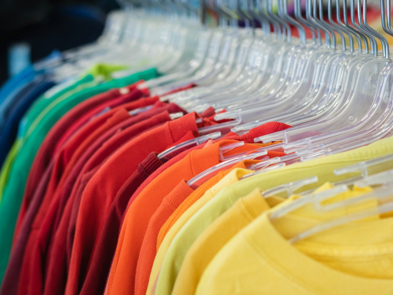 Rack of t-shirts on hangers in a rainbow of colors